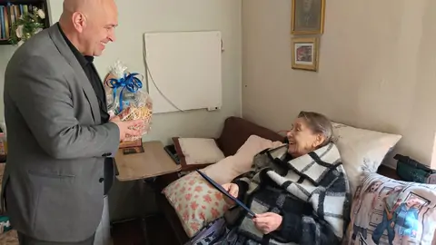 Zdjęcie Wójta Gminy Mogilany wręczającego prezent jubilatce - Pani Genowefie.