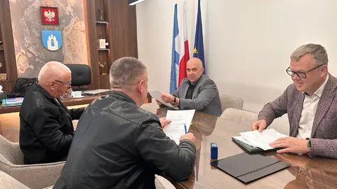 4 osoby siedzące przy biurku w gabinecie Wójta. 
