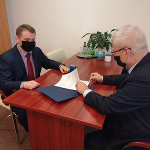 Wójt Piotr Piotrowski podpisuje umowę o dofinansowanie w obecności pracownika Urzędu Marszałkowskiego.