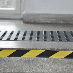 Ciąg schodów oznakowany czarnymi pasami ostrzegawczymi.
